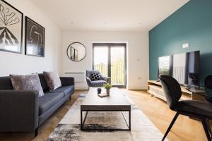 a living room with a couch and a tv at Staines Riverside by Charles Hope in Staines