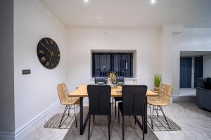 a dining room table with chairs and a clock on the wall at Modern 2-Bed Townhouse, Conveniently Located Near Leeds City Centre - Perfect for Corporate Stays in Farnley