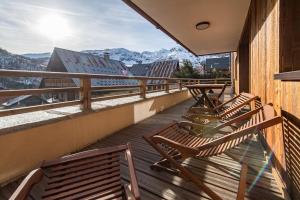 a balcony with wooden chairs and a view of mountains at Bel appartement 6 personnes avec deux terrasses ensoleillées au coeur du village in Saint-Sorlin-dʼArves