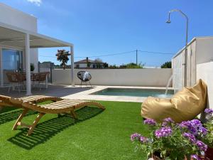 un patio trasero con piscina, banco y césped en Villas Florida, en Conil de la Frontera