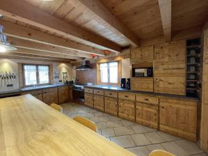 a large kitchen with wooden cabinets and a wooden table at Chalet montagnard 15 personnes - proche du centre du village in Saint-Sorlin-dʼArves