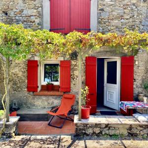 una casa roja con puertas rojas y una silla naranja en Maison d'une chambre avec piscine partagee terrasse et wifi a Lignairolles en Lignairolles