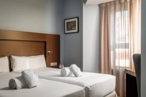 a hotel room with two beds and a window at Hotel Madanis Liceo in Hospitalet de Llobregat