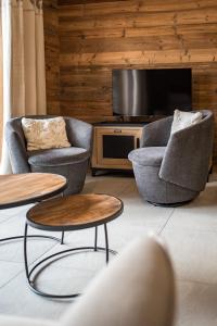 sala de estar con 2 sillas y TV de pantalla plana en Appartement neuf au cœur du village - 6 personnes en Saint-Sorlin-dʼArves
