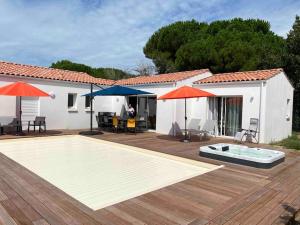 een huis met een zwembad en twee parasols bij Villa Les Sables Vigniers, Piscine et Jacuzzi prives, plage à 800m in Les Sables Vignier