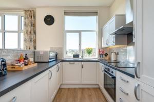 a kitchen with white cabinets and a black counter top at Cofton Holidays in Dawlish