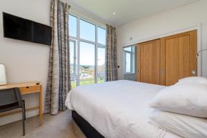a bedroom with a bed and a large window at Cofton Holidays in Dawlish
