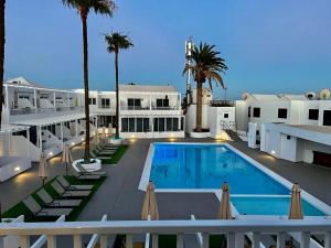 a swimming pool with palm trees and a building at Alecu Home in Puerto del Carmen
