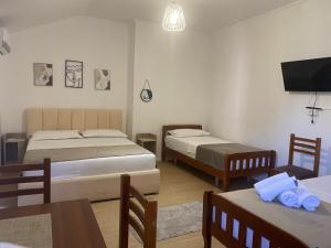 a room with two beds and a table and a tv at Vila M Vera Studios and Apartments in Durrës