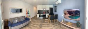 a living room with a blue couch and a kitchen at Alecu Home in Puerto del Carmen +3 photos