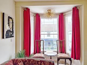 Habitación con cortinas rojas, 2 sillas y ventana en Sunbeams, en Chichester