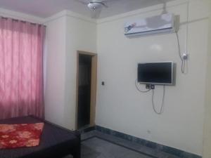 um quarto com uma cama e uma televisão na parede em Kashmir Inn Hotel em Muzaffarabad