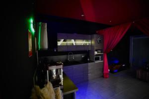 a dark kitchen with a sink and a red curtain at L unique Cinéma Room in Grenoble