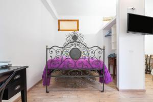 a purple bed in a room with a tv at Alla Marina Cagliari in Cagliari