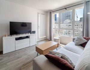 ein Wohnzimmer mit einem Sofa und einem Flachbild-TV in der Unterkunft Skyview appartement la Défense in Courbevoie