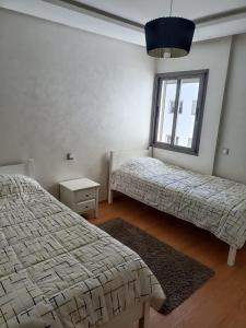 1 dormitorio con 2 camas y ventana en Appartement au Parc Mohammedia, en Mohammedia