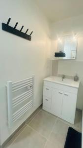 La salle de bains blanche est pourvue d'un lavabo et d'un miroir. dans l'établissement Escale en Provence, à Sainte-Tulle