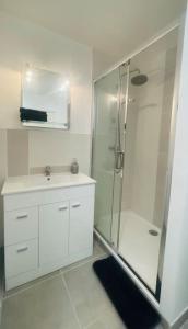 La salle de bains blanche est pourvue d'une douche et d'un lavabo. dans l'établissement Escale en Provence, à Sainte-Tulle