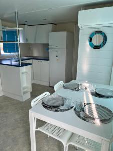 a kitchen with a white table with plates and chairs at Bungalow bleu in Roquebrune-sur-Argens