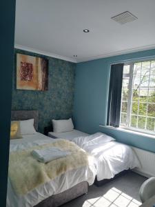 2 camas en una habitación con paredes azules y ventana en An Exquisite Deluxe Room in a Hotel - Free Parking - with access to Resturant - Shisha Bar- Wine Bar, en Roundhay
