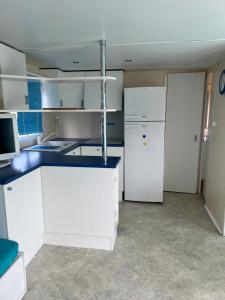 a kitchen with white cabinets and a refrigerator at Bungalow bleu in Roquebrune-sur-Argens