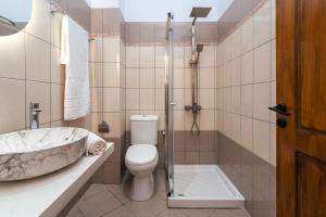 a bathroom with a toilet and a sink and a shower at C'est La Vie Rooms and Suites in Laganas