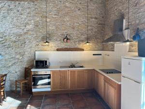 a kitchen with wooden cabinets and a stone wall at Le Clos Sainte Marie - Caune in Cenne-Monestiès