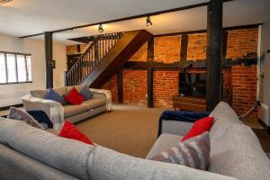 una sala de estar con 2 sofás y una pared de ladrillo en The Cottage by StayStaycations 