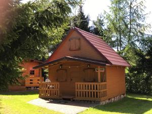 a small house with a red roof on a yard at Domki nad jeziorem Mrągowo-Marcinkowo in Mrągowo
