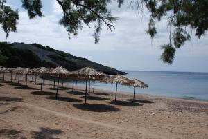 una fila de sombrillas de paja en una playa en LYGIROS ANASTASIOS, en Tarti