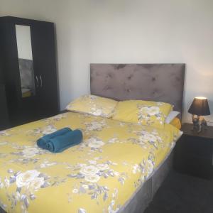 Una cama con un edredón amarillo con una bolsa azul. en The Old White Hart Brewery Guesthouse en Bath