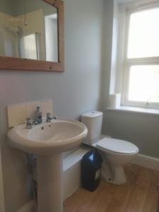 a bathroom with a sink and a toilet and a mirror at The Old White Hart Brewery Guesthouse in Bath