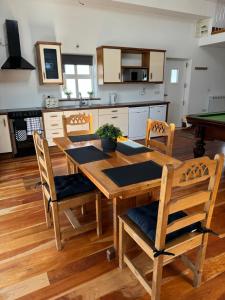 a kitchen with a wooden table with chairs and a pool table at De Búrca Cottage KERRY in Brackhill