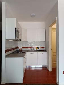 cocina con armarios blancos y suelo de baldosa roja en Casa Lucia, en Negrar