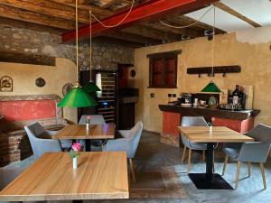 a restaurant with wooden tables and chairs and green lamps at Villa Rose in Cividale del Friuli