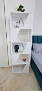 a white book shelf with a bonsai plant on it at Oasis in Durrës