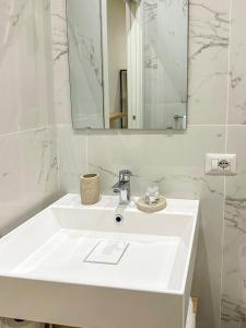 La salle de bains blanche est pourvue d'un lavabo et d'un miroir. dans l'établissement CasaMarì, à Torre del Greco