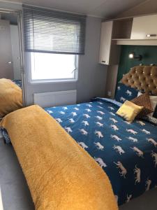 ein Schlafzimmer mit einem Bett mit einer blauen Bettdecke und Pferden darauf in der Unterkunft Seabreeze, Utopia, Shorefield Country Park, Milford on Sea, Shorefield Road, SO41 0LH, United Kingdom in Milford on Sea