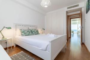 a white bedroom with a white bed and a hallway at Akicity Jamor Selected in Cruz Quebrada