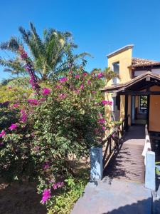a house with pink flowers on the side of it at Pousada e Camping Solar de Itaunas in Itaúnas
