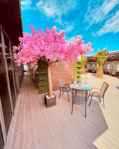 einen rosa Baum auf einer Terrasse mit einem Tisch und Stühlen in der Unterkunft Plaza Hotel Plovdiv in Plowdiw