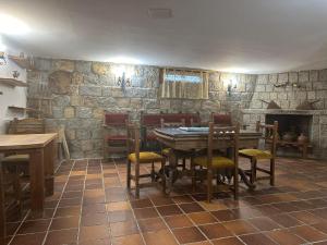 a dining room with a table and chairs and a stone wall at Cordel in La Serrada