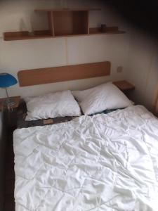 ein Bett mit weißer Bettwäsche und Kissen darauf in der Unterkunft Mobilní dům Venda in Hradišťko