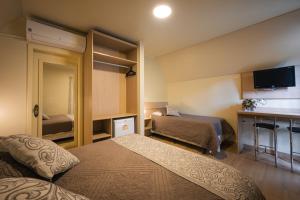 a hotel room with two beds and a tv at Hotel Cabanas Alto Da Serra in Canela