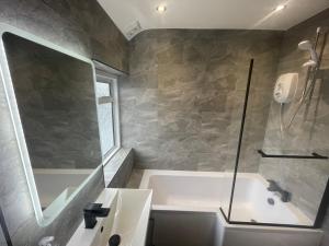 La salle de bains est pourvue d'une baignoire et d'une douche en verre. dans l'établissement 2 Bed Flat near Heathrow Airport & Elizabeth Line, à Hayes