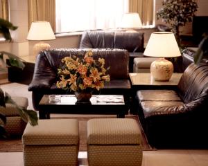 リスボンにあるAparthotel VIP Executive Suites do Marquêsのリビングルーム(革張りのソファ、花のテーブル付)
