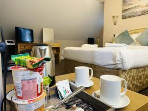 a hotel room with two beds and a table with two mugs at woodcock inn in Felbridge