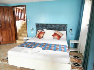 una camera da letto con un grande letto con pareti blu di Studio a Grand Popo a 10 m de la plage avec piscine partagee jardin clos et wifi a Grand-Popo