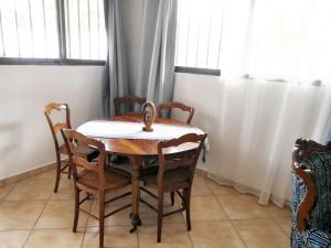 una mesa y sillas en una habitación con ventanas en Studio a Grand Popo a 10 m de la plage avec piscine partagee jardin clos et wifi, en Grand-Popo