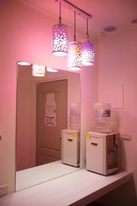Zimmer mit rosa Wänden, 2 Kühlschränken und Lampen in der Unterkunft Anshun Hotel in Taichung
